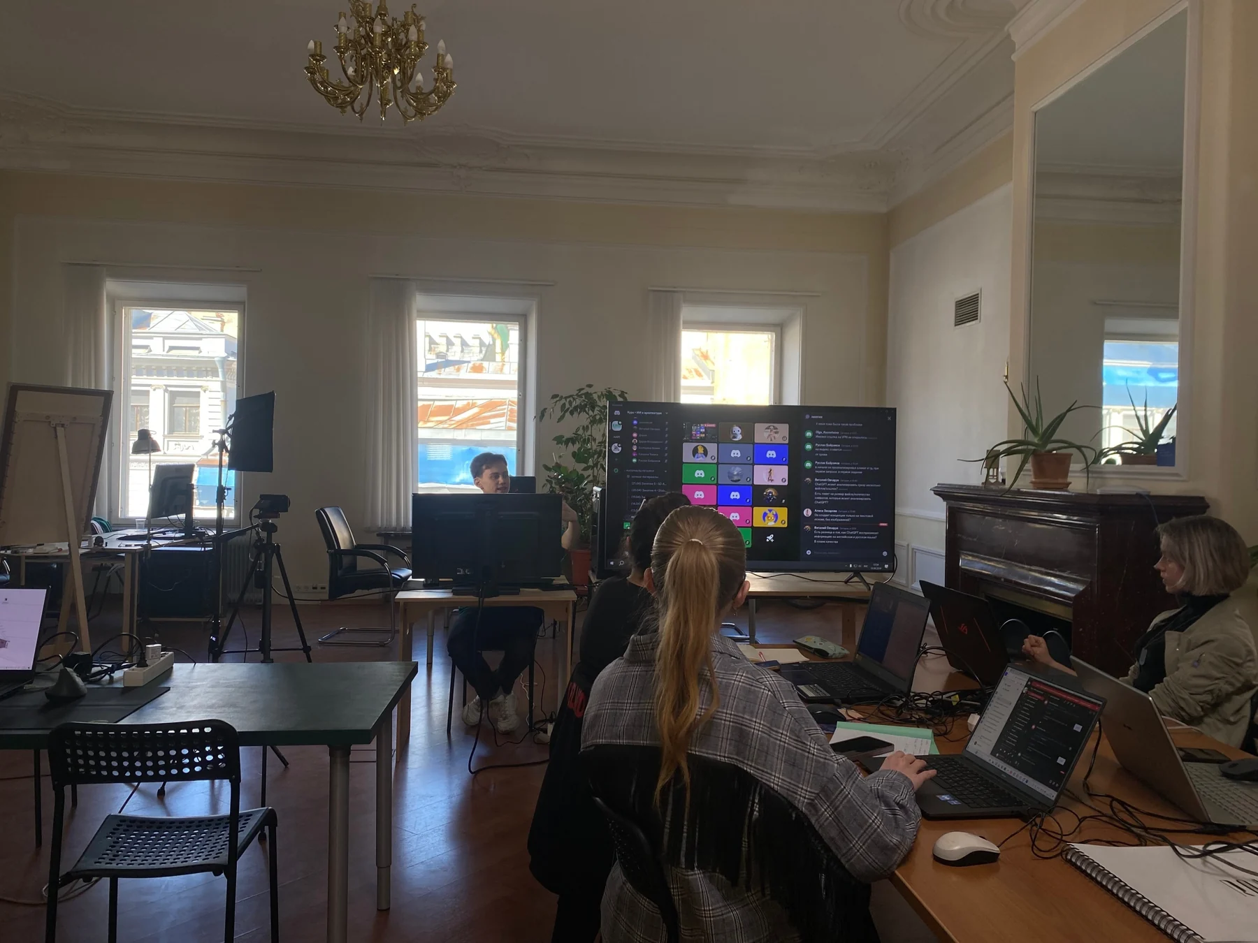 Занятие в мастерской: Егор за преподавательским столом, участники работают за ноутбуками